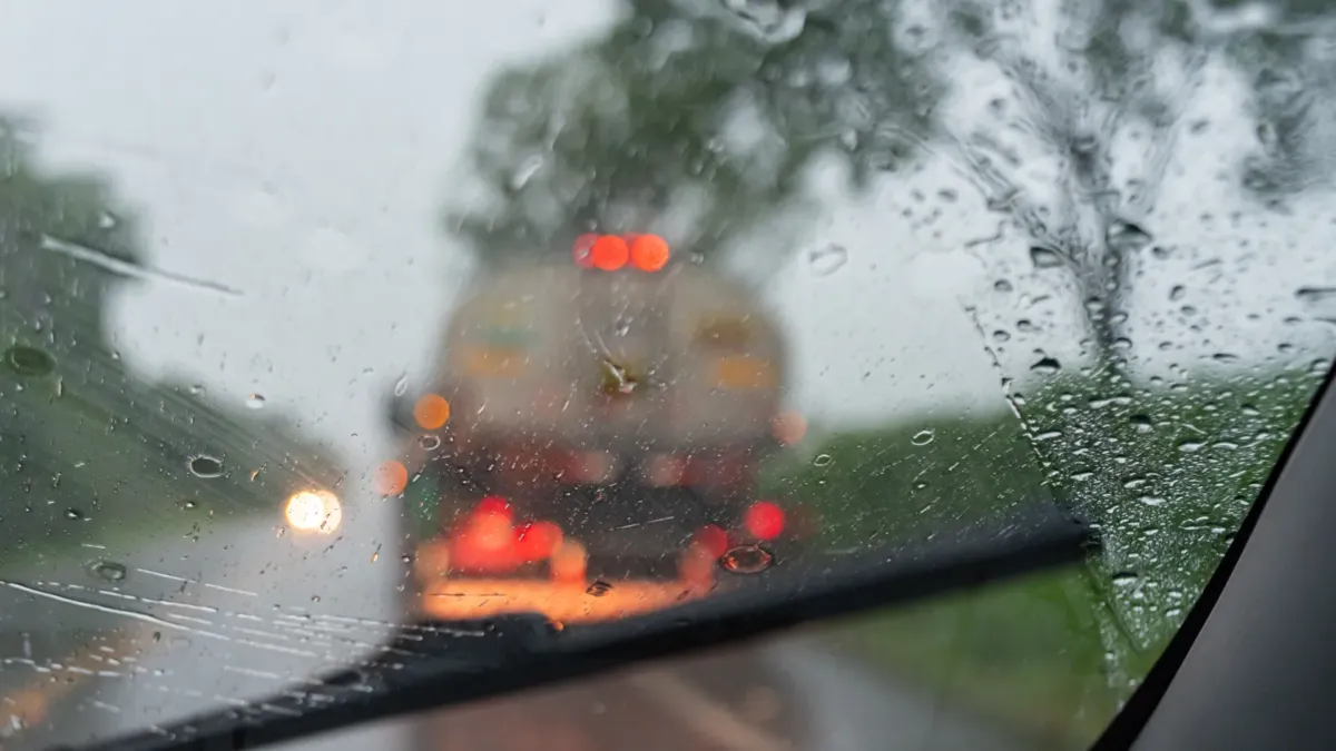 Pohled přes mokré čelní sklo na nákladní auto v hustém dešti