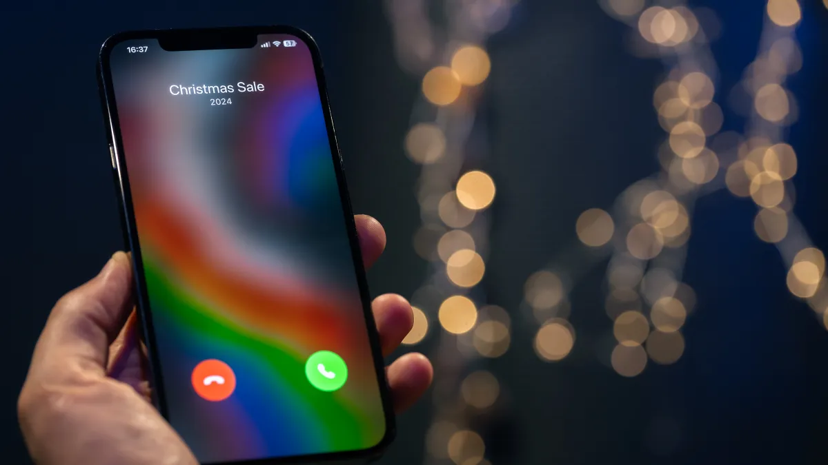 Ruka drží telefon s obrazovkou příchozího hovoru