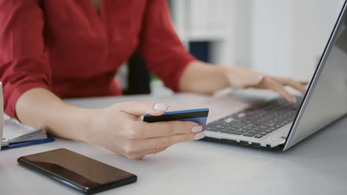 Ruce s platební kartou u notebooku při nákupu na internetu