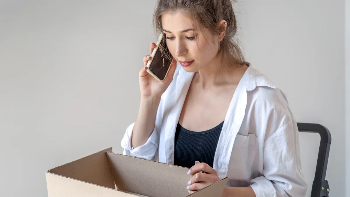 Žena telefonuje nad krabicí s balíkem