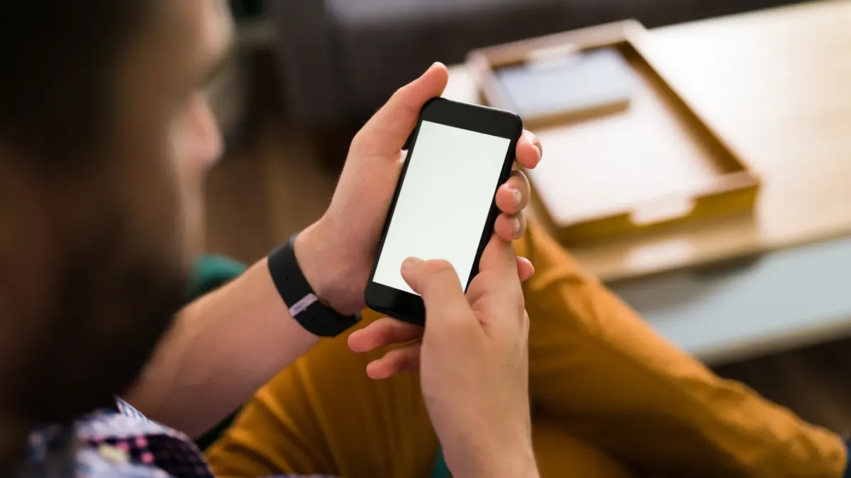 Muž drží v rukou chytrý telefon a čte zprávu