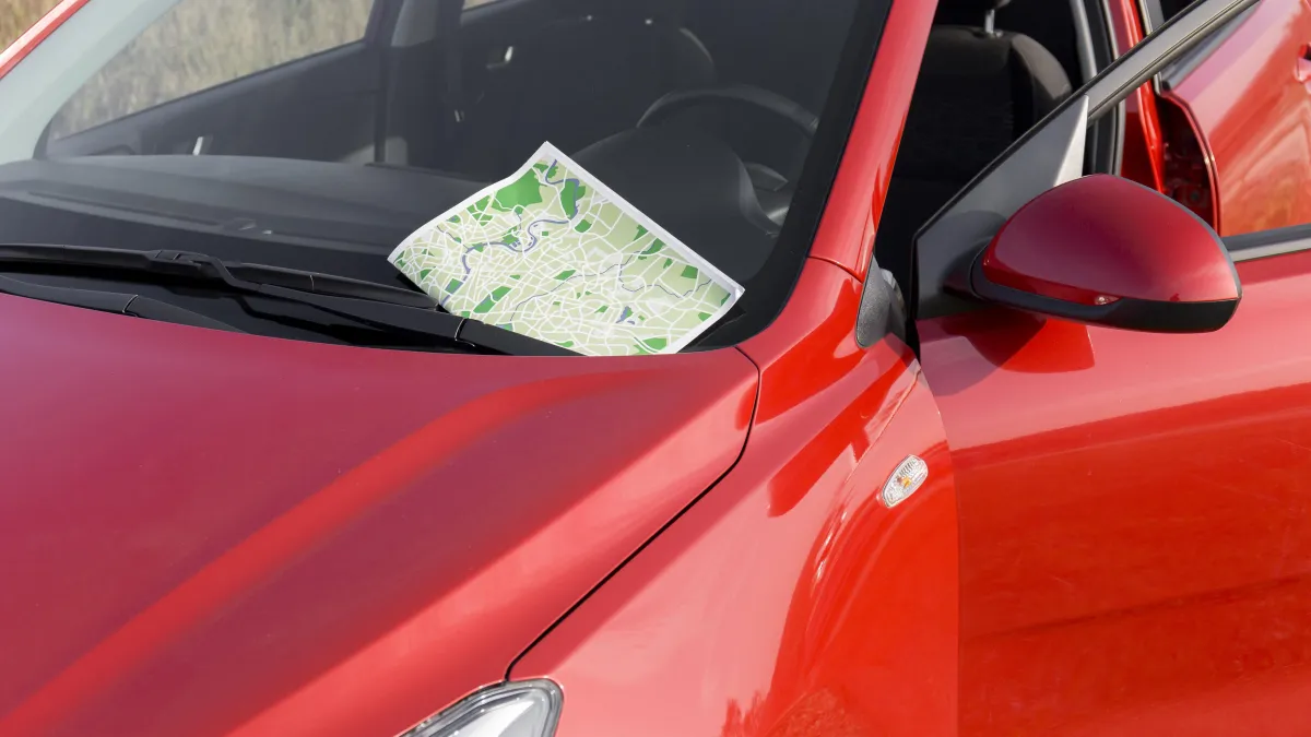 Zaparkované červené auto s papírem za čelním sklem