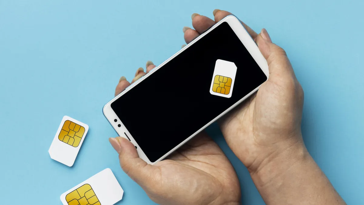 Ruce drží chytrý telefon a SIM karty